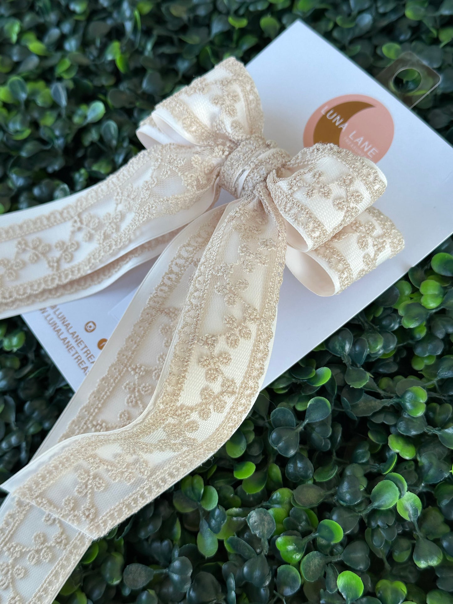Enhance your hairstyle with the tan Coquette Hair Bow. This 5 inch wide and 8 inch long hair bow is made with delicate lace and satin matte ribbon for a sophisticated touch. Add a touch of elegance to any outfit with this stylish hair accessory.     comes attached to a French Barrett
