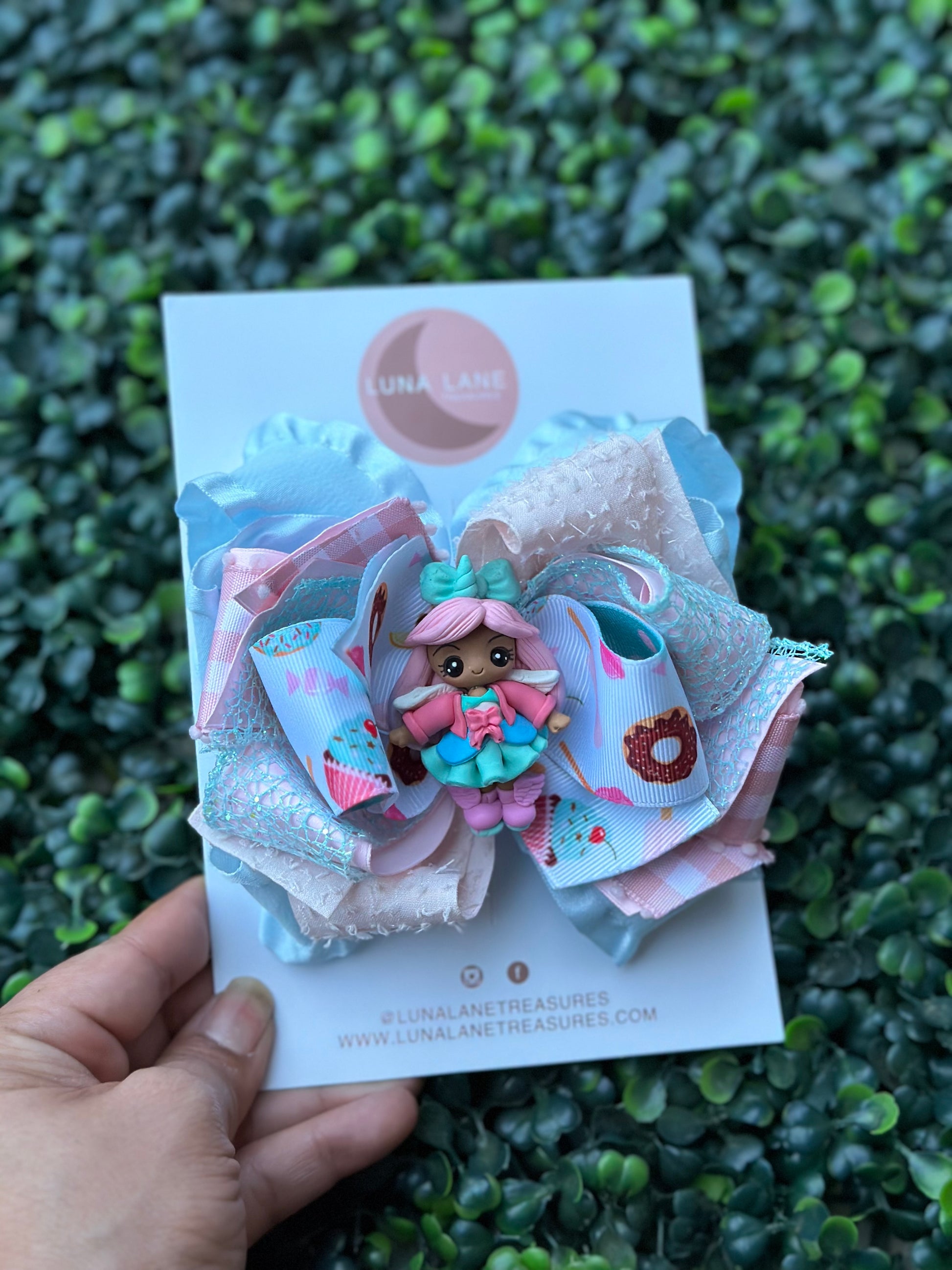  The Cupcake doll Lane Ruffle Bow is a 5 inch handmade hair bow that features layers of Grosgrain and ruffle ribbons. Perfect for girls or infants, it comes with a clay doll center attached to either an alligator clip or nylon headband. Add a fun and stylish touch to any outfit with this unique accessory.