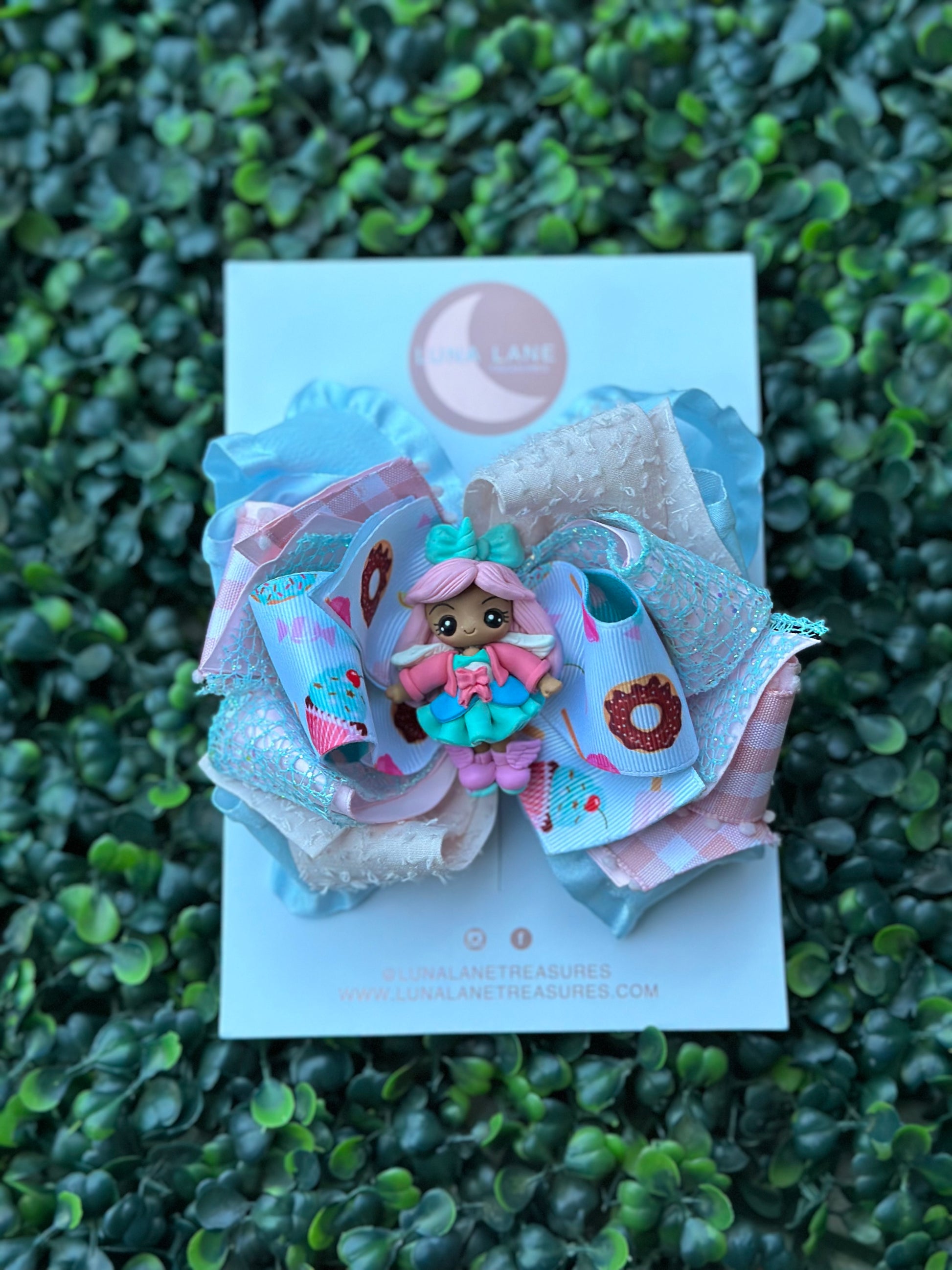  The Cupcake doll Lane Ruffle Bow is a 5 inch handmade hair bow that features layers of Grosgrain and ruffle ribbons. Perfect for girls or infants, it comes with a clay doll center attached to either an alligator clip or nylon headband. Add a fun and stylish touch to any outfit with this unique accessory.