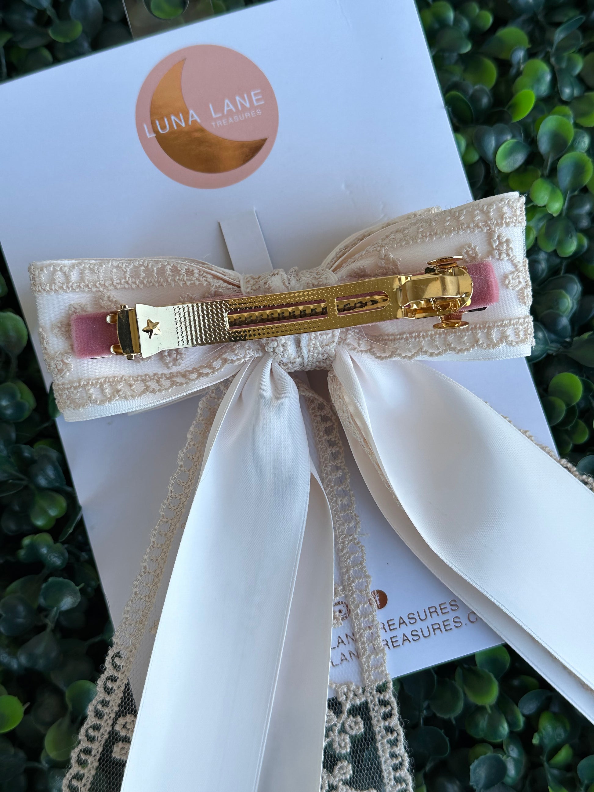 Enhance your hairstyle with the tan Coquette Hair Bow. This 5 inch wide and 8 inch long hair bow is made with delicate lace and satin matte ribbon for a sophisticated touch. Add a touch of elegance to any outfit with this stylish hair accessory.     comes attached to a French Barrett