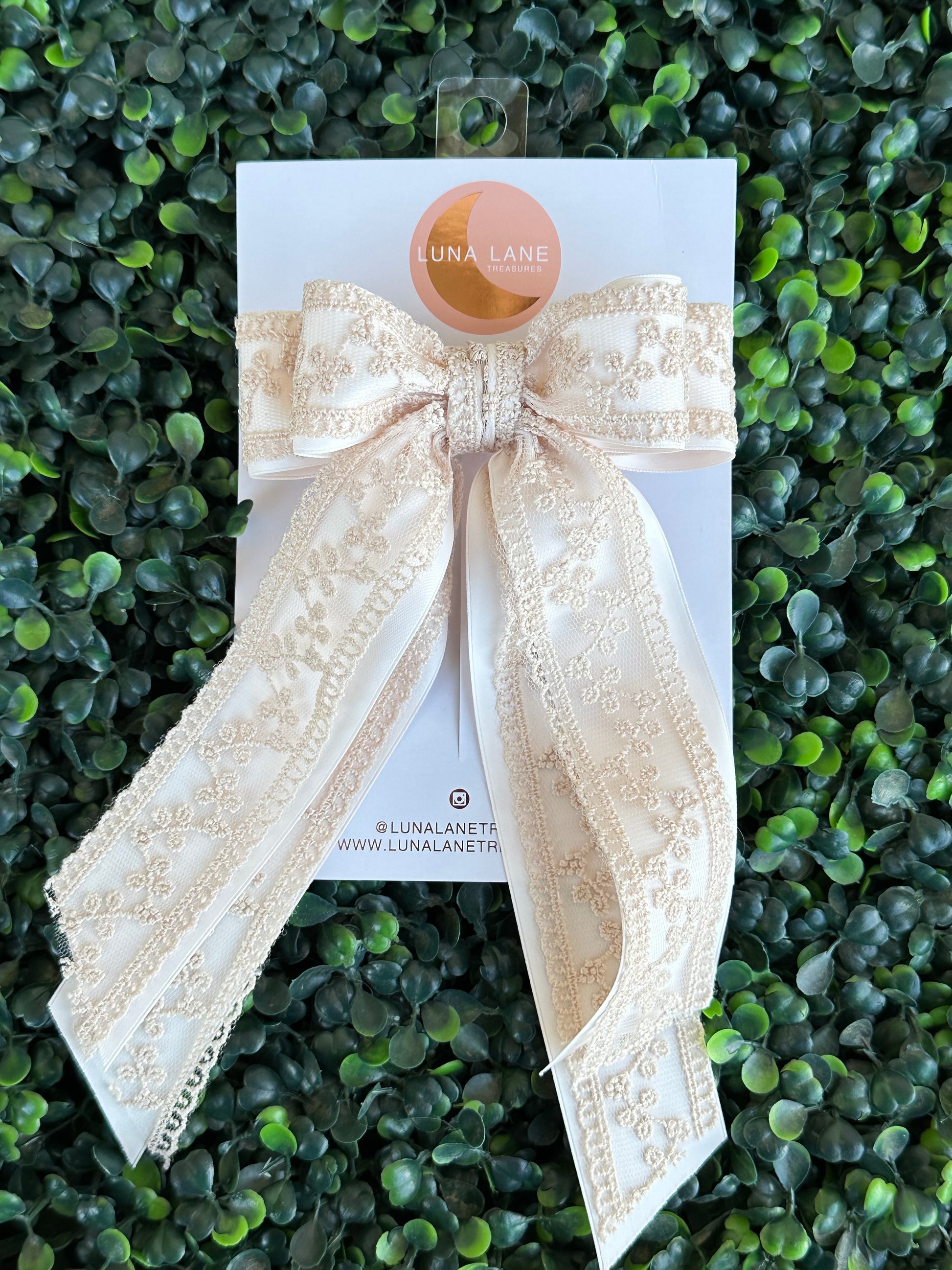 Enhance your hairstyle with the tan Coquette Hair Bow. This 5 inch wide and 8 inch long hair bow is made with delicate lace and satin matte ribbon for a sophisticated touch. Add a touch of elegance to any outfit with this stylish hair accessory.     comes attached to a French Barrett