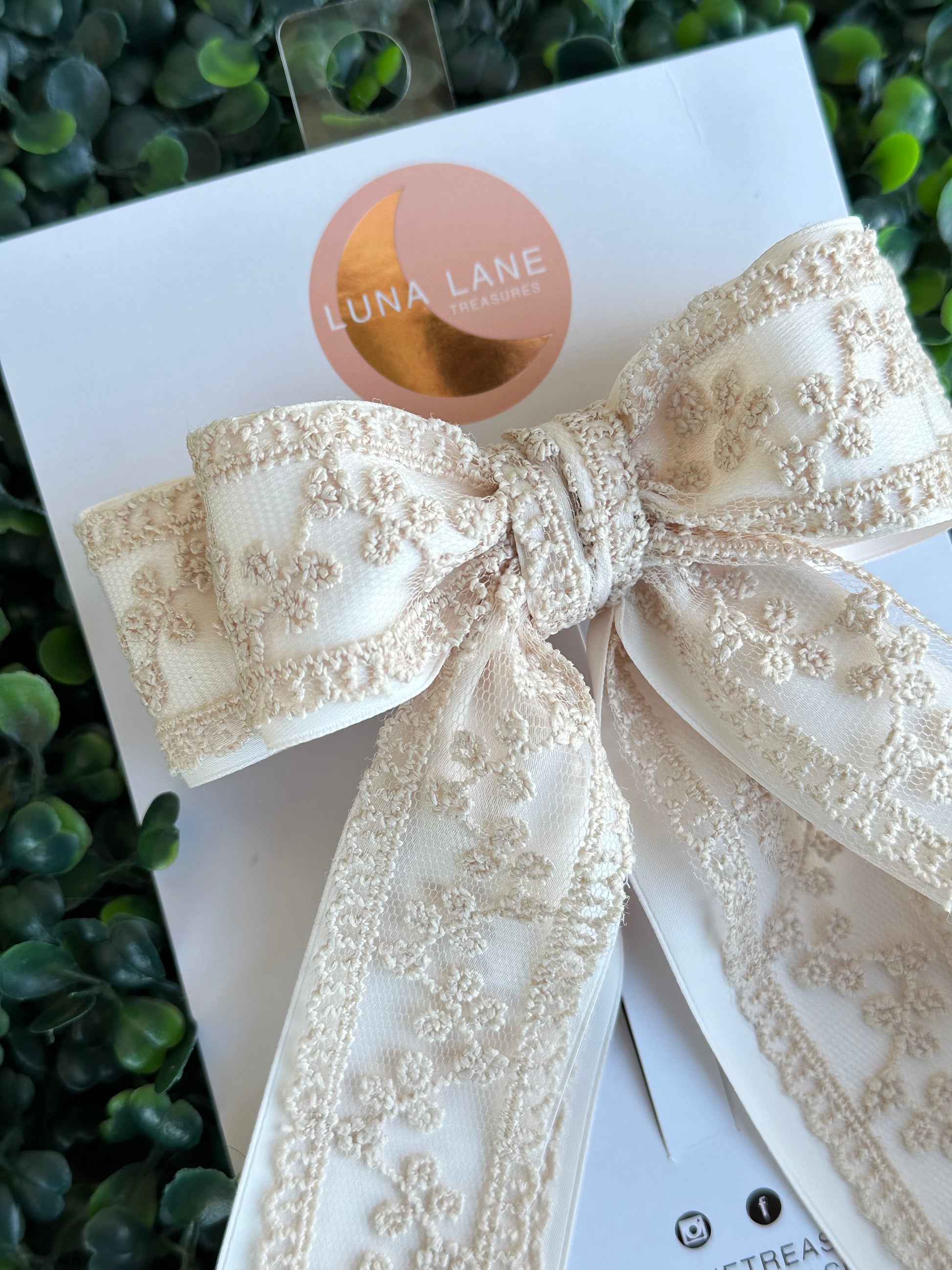 Enhance your hairstyle with the tan Coquette Hair Bow. This 5 inch wide and 8 inch long hair bow is made with delicate lace and satin matte ribbon for a sophisticated touch. Add a touch of elegance to any outfit with this stylish hair accessory.     comes attached to a French Barrett